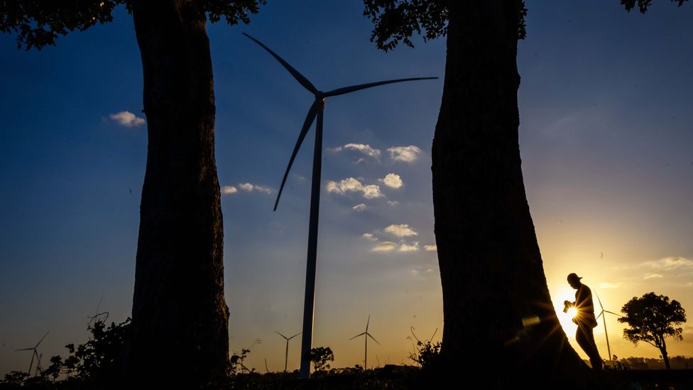 A man walks past wind turbines in Indonesia at dusk (Credit: Getty Images)