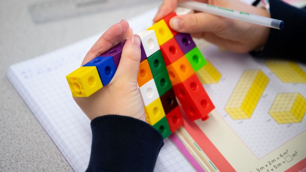 A primary school child uses coloured cubes to study maths in a school in the UK (Credit: Getty Images)