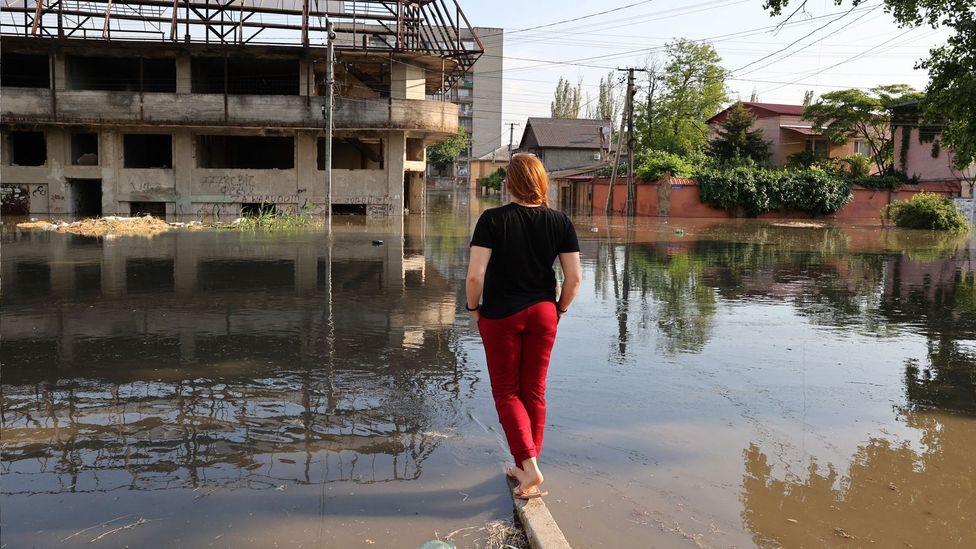 A woman looks at a flooded street in the town of Kherson (Credit: Getty Images)